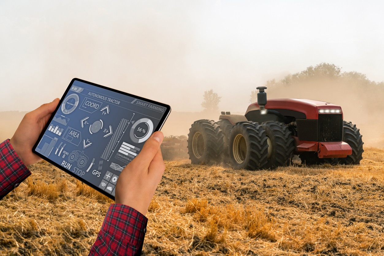 A farmer with digital tablet controls an autonomous tractor on a smart farm. Vector illustration EPS 10